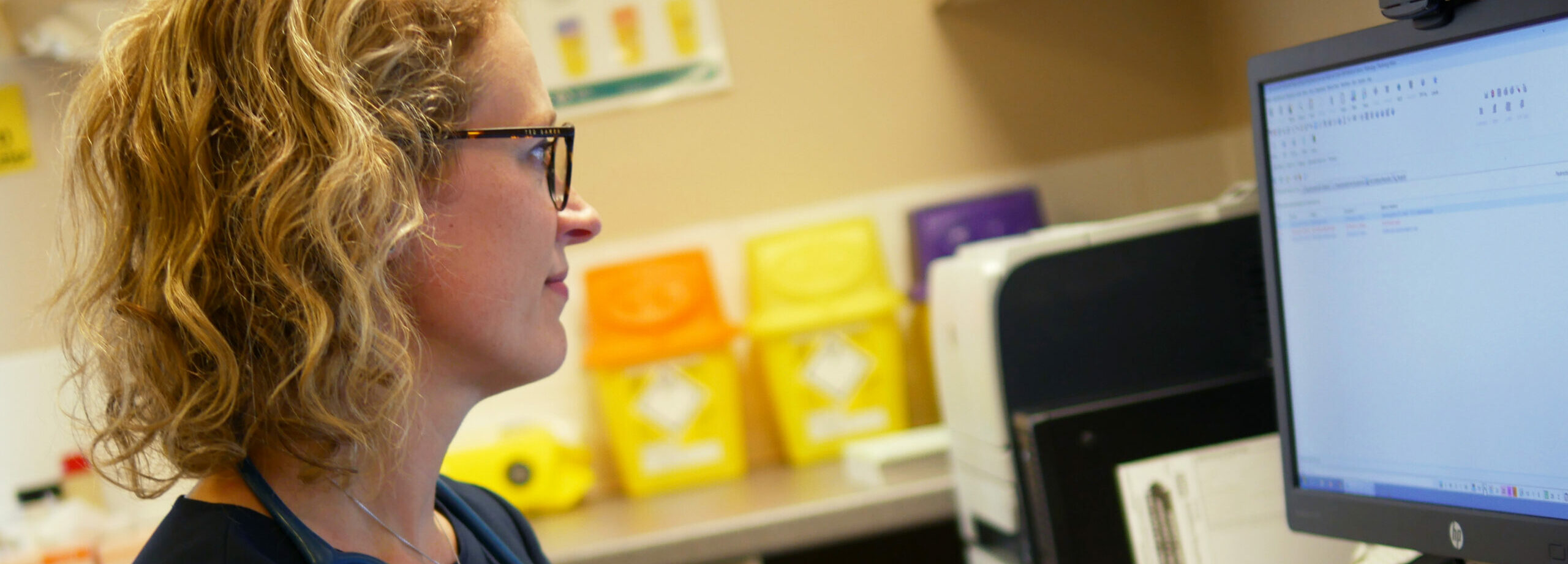 A healthcare worker uses a computer in an office environment. 